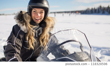 Happy young woman on a snowmobile outdoors on a sunny winter day. Beautiful girl riding outside on a cold winter day. Girl on a snow mobile. 118328506