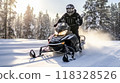 A man riding on a snowmobile through a snowy forest on a sunny winter day. Guy riding outside on a cold winter day. A man is riding on a snow mobile in a snowy forest. 118328526