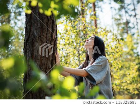 A young girl hugs a tree in the forest. 118328685