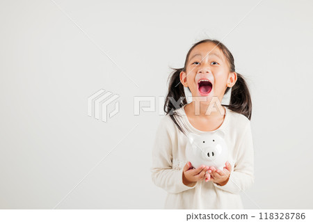 Asian little kid girl holding piggy bank and looking at camera at studio isolated on white background, Happy kindergarten child lifestyle smiling with is white piggybank, Thai personal money savings Asian little kid girl holding piggy bank and looking at camera at studio isolated on white background, Happy kindergarten child lifestyle smiling with is white piggybank, Thai personal money savings 118328786