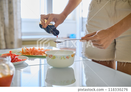 Preparing a flavorful dish by adding oyster sauce to a bowl in a bright kitchen setting Preparing a flavorful dish by adding oyster sauce to a bowl in a bright kitchen setting 118330276