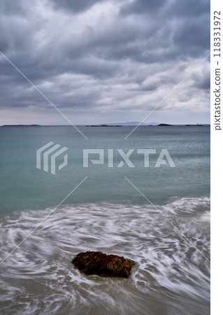 long exposure beach waves around rock cloudy day 118331972
