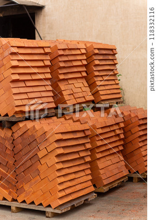 Stacks of new, red ceramic brick stacked on wooden pallets. Stacks of new, red ceramic brick stacked on wooden pallets. 118332116