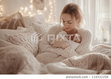 Young mother holding her newborn baby on a cozy bed 118332208