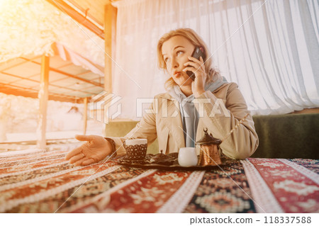 Woman Talking on Phone at a Cafe Table with Turkish Coffee 118337588