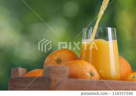 orange juice pouring in glass and ripe fruits near in crate orange juice pouring in glass and ripe fruits near in crate 118337590