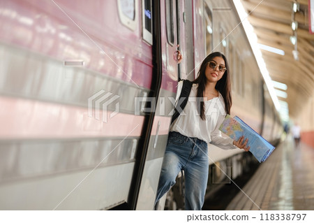 A woman is standing on a train platform holding a map 118338797