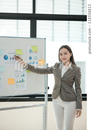 A woman is standing in front of a white board with a presentation on it A woman is standing in front of a white board with a presentation on it 118338813