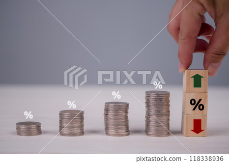 Stacked coins with percentage symbols showing financial growth and market trends, hand holding wooden blocks with arrows and percentage signs 118338936