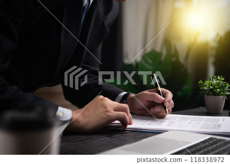 Businessman signing a document at desk, closeup on hand and pen. Represents professionalism, formal agreement, contract completion. Perfect for legal, corporate contexts. 118338972