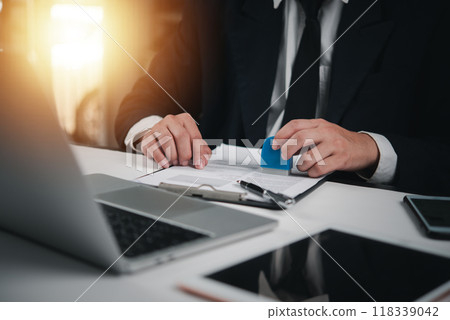 Businessman in suit stamping a document, approving contract. Professional corporate setup for legal agreements, official paperwork. Signature, authority process. Businessman in suit stamping a document, approving contract. Professional corporate setup for legal agreements, official paperwork. Signature, authority process. 118339042