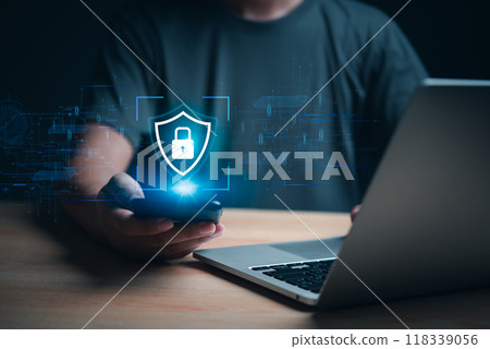 Hand holding smartphone with cybersecurity hologram, laptop in background. Represents data protection and digital security. Great for tech firms, cybersecurity awareness, and online privacy. Hand holding smartphone with cybersecurity hologram, laptop in background. Represents data protection and digital security. Great for tech firms, cybersecurity awareness, and online privacy. 118339056