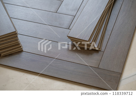 Laying laminate flooring in a home renovation project. Detailed image of wood planks being carefully aligned in a modern apartment setting 118339712