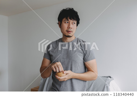 Man eating snacks peanuts in the house to increase his protein and magnesium. Man eating snacks peanuts in the house to increase his protein and magnesium. 118340440