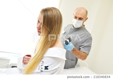 A dermatologist examines neoplasms on the patient's skin using a special dermatoscope device. Prevention of melanoma. 118340834