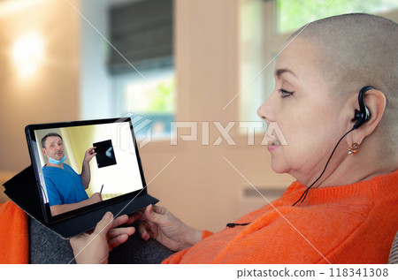 Cancer survivor participates in virtual medical discussion, attentively listening to doctor's explanation of X-ray findings on tablet. Cancer survivor participates in virtual medical discussion, attentively listening to doctor's explanation of X-ray findings on tablet. 118341308