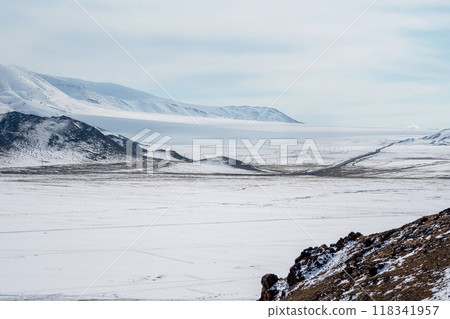 The road is far away through the snow-capped hills. Mongolia. The road is far away through the snow-capped hills. Mongolia. 118341957
