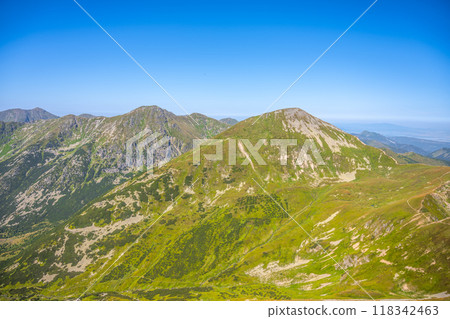 The picturesque landscape of the Western Tatras showcases lush green slopes under a clear blue sky, inviting hikers and nature lovers to explore its scenic beauty during summer. 118342463