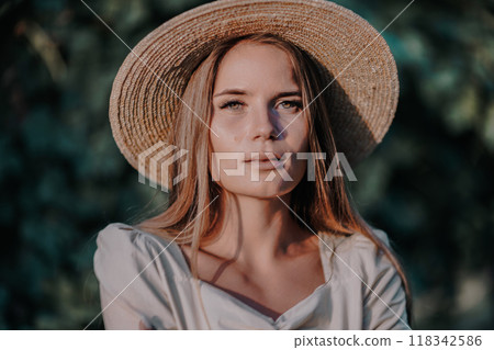 Woman with straw hat stands in front of vineyard. She is wearing a light dress and posing for a photo. Travel concept to different countries 118342586
