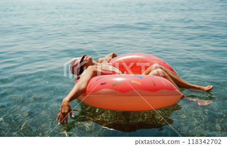 Summer vacation woman in hat floats on an inflatable donut mattress. Happy woman relaxing and enjoying family summer travel holidays travel on the sea. 118342702