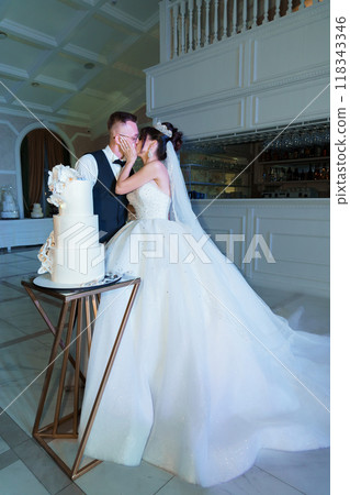 Elegant Wedding Celebration with Bride and Groom Sharing a Moment Beside Their Exquisite Wedding Cake in Romantic Venue Elegant Wedding Celebration with Bride and Groom Sharing a Moment Beside Their Exquisite Wedding Cake in Romantic Venue 118343346