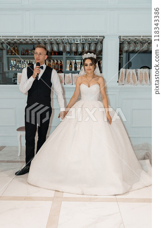 Elegant Wedding Celebration with Bride and Groom Holding Hands During Reception Toast 118343386