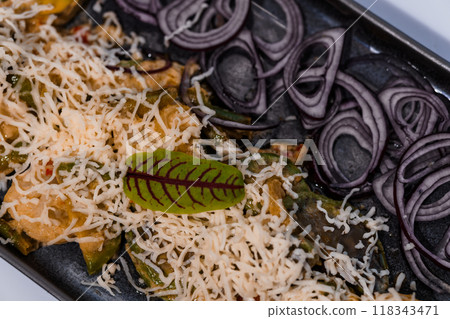 Gourmet Presentation of Grated Cheese Over Sliced Vegetables with Elegant Garnish on a Slate Gray Tray 118343471