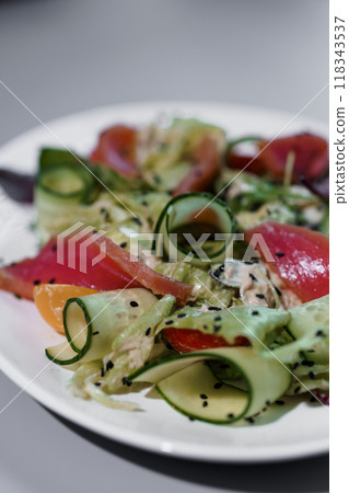 Fresh Vibrant Salad with Zucchini Curls, Tuna, and Black Sesame Seeds on a White Plate Fresh Vibrant Salad with Zucchini Curls, Tuna, and Black Sesame Seeds on a White Plate 118343537