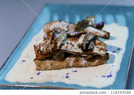 Gourmet Artistry: Savory Grilled Mushrooms on Creamy Sauce with Purple Garnish on Elegant Blue Plate Gourmet Artistry: Savory Grilled Mushrooms on Creamy Sauce with Purple Garnish on Elegant Blue Plate 118343580