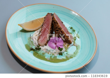 Gourmet Seared Tuna with Decorative Edible Flower and Lemon Wedge on Elegant Plate Gourmet Seared Tuna with Decorative Edible Flower and Lemon Wedge on Elegant Plate 118343619