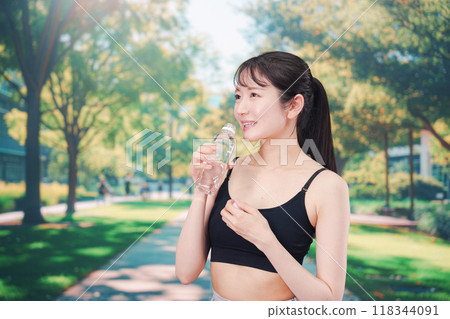 年輕女子在外面跑步時喝水 118344091