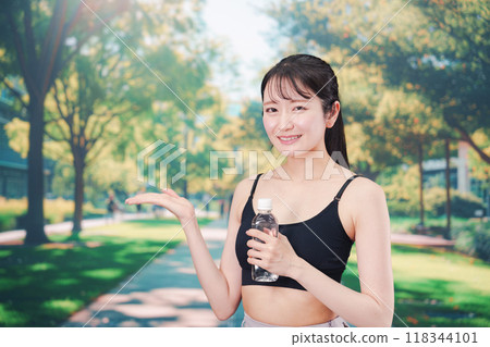 年輕女子在外面跑步時喝水 年輕女子在外面跑步時喝水 118344101