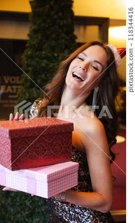 Girl holding Christmas present near New Year tree. Happiness emotions 118344416