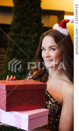 Girl holding Christmas present near New Year tree. Happiness emotions Girl holding Christmas present near New Year tree. Happiness emotions 118344419