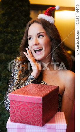 Girl holding Christmas present near New Year tree. Happiness emotions 118344446