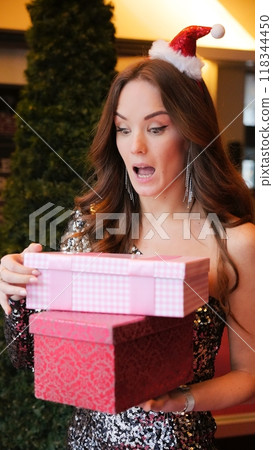 Girl holding Christmas present near New Year tree. Happiness emotions Girl holding Christmas present near New Year tree. Happiness emotions 118344450