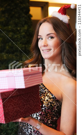 Girl holding Christmas present near New Year tree. Happiness emotions Girl holding Christmas present near New Year tree. Happiness emotions 118344451