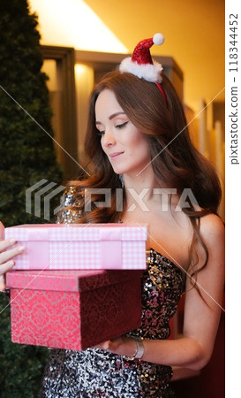 Girl holding Christmas present near New Year tree. Happiness emotions Girl holding Christmas present near New Year tree. Happiness emotions 118344452