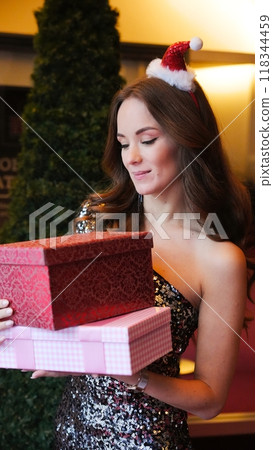 Girl holding Christmas present near New Year tree. Happiness emotions Girl holding Christmas present near New Year tree. Happiness emotions 118344459