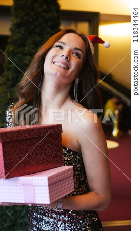 Girl holding Christmas present near New Year tree. Happiness emotions Girl holding Christmas present near New Year tree. Happiness emotions 118344464
