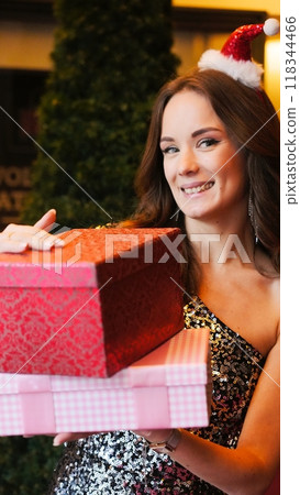 Girl holding Christmas present near New Year tree. Happiness emotions Girl holding Christmas present near New Year tree. Happiness emotions 118344466