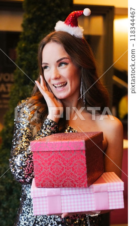 Girl holding Christmas present near New Year tree. Happiness emotions Girl holding Christmas present near New Year tree. Happiness emotions 118344467