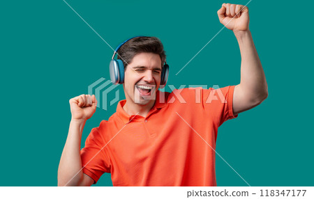 Young positive man listening music, enjoying with headphones, blue studio 118347177
