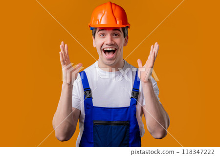 Shocked industrial specialist worker in helmet man glad, he screaming WOW. Impressed guy trying to get attention on orange background. 118347222