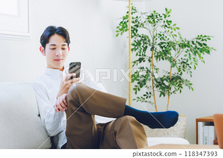 A young man looking at his smartphone in the living room A young man looking at his smartphone in the living room 118347393