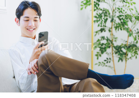 年輕人在客廳看智慧型手機 118347408