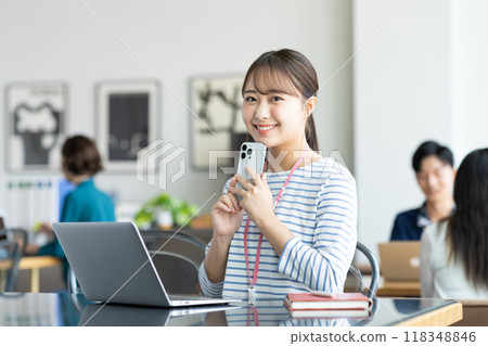 操作一個智能手機的少婦在辦公室 118348846