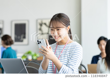 操作一個智能手機的少婦在辦公室 118348847