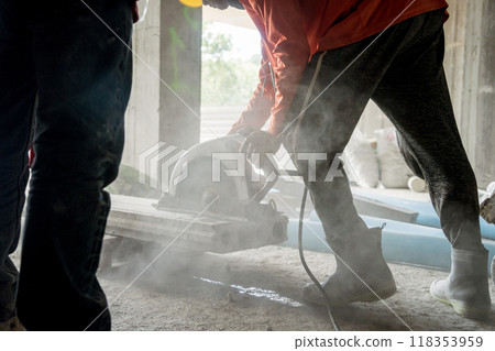 A builder using a circular saw to cut a large concrete piece 118353959