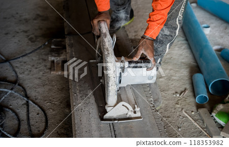 A builder using a circular saw to cut a large concrete piece 118353982